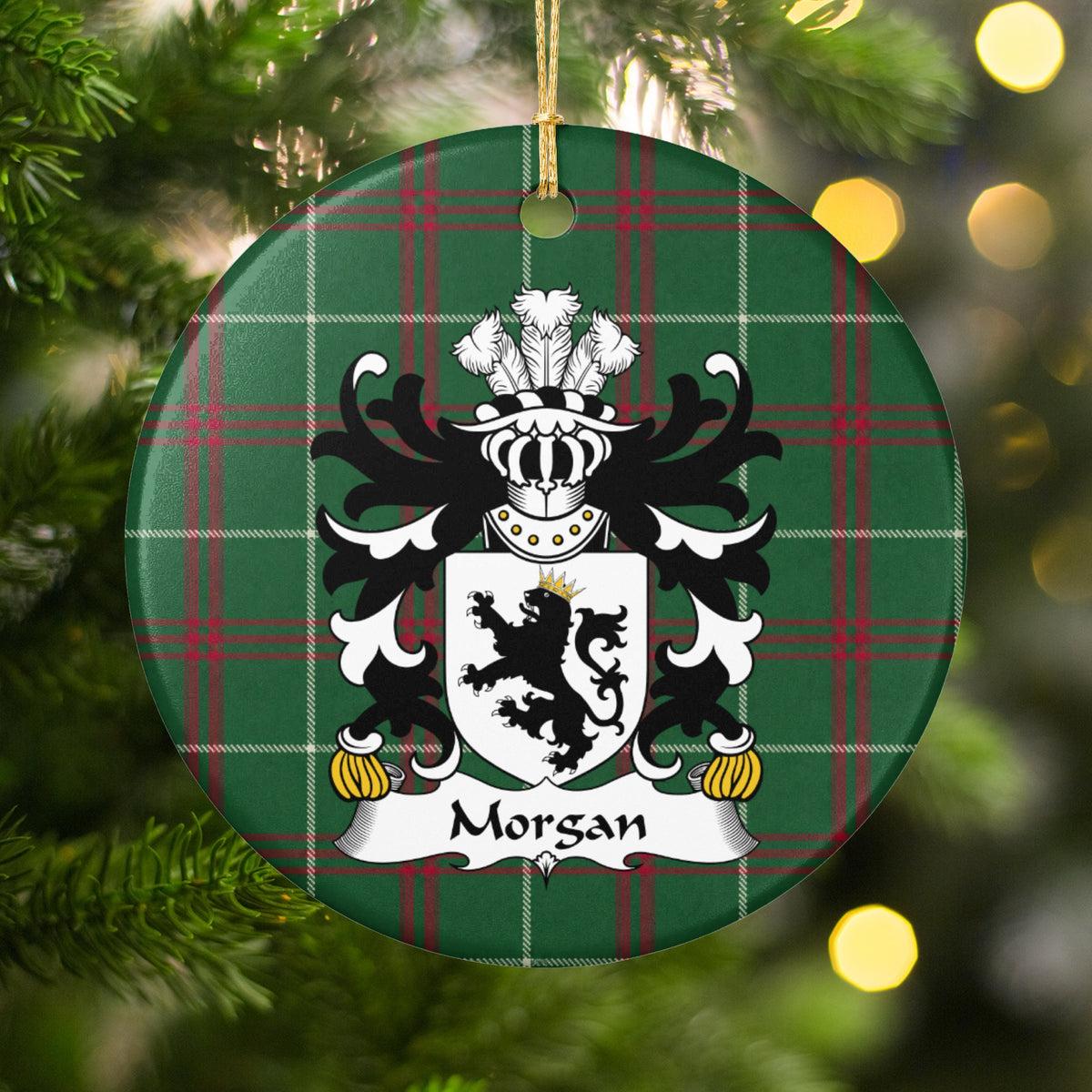 Morgan ornament, Style 3 hanging among Christmas tree branches and warm lights; a crowned black lion on a white shield on Welsh national tartan.
