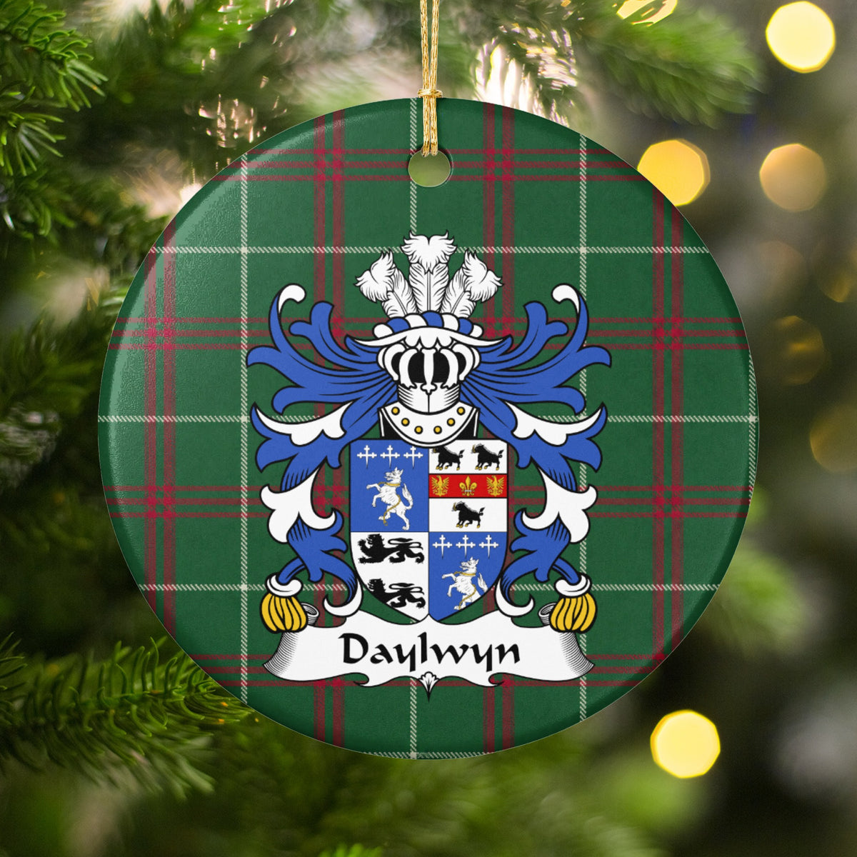 Daylwyn ornament hanging among Christmas tree branches and warm lights; a quartered blue-and-white shield with lions, dark animals and small cross motifs on Welsh national tartan.