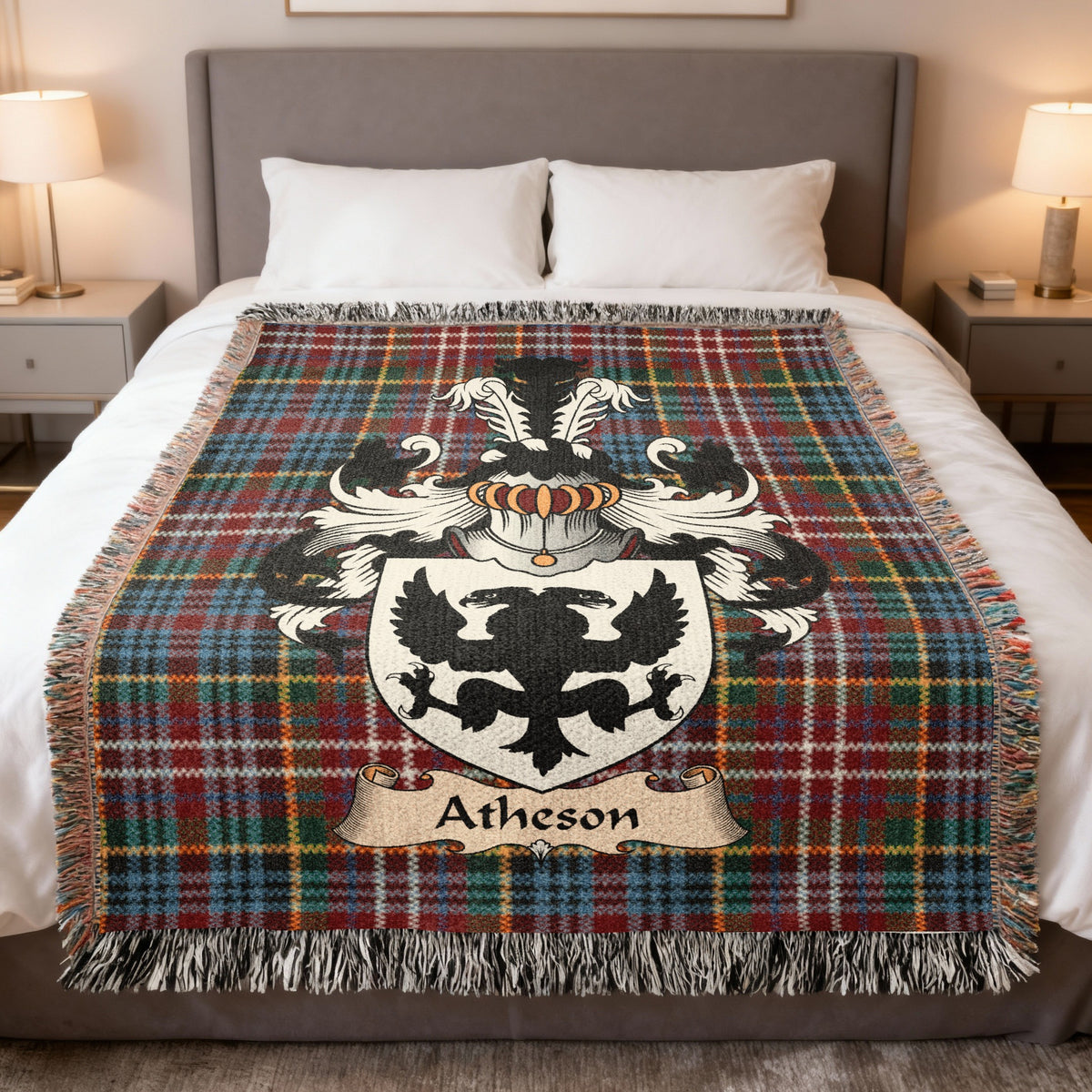 Atheson Scottish family crest woven blanket on a Caledonia tartan background, displayed on a bed
