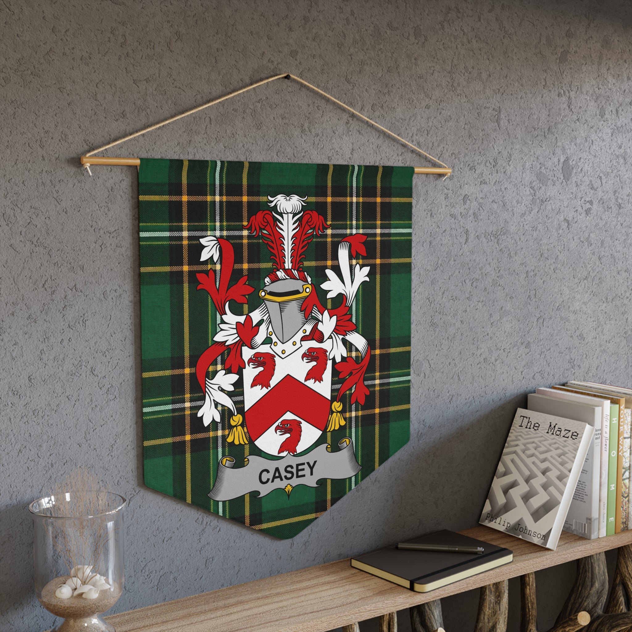 Casey family crest on green plaid banner hanging on wall with books.