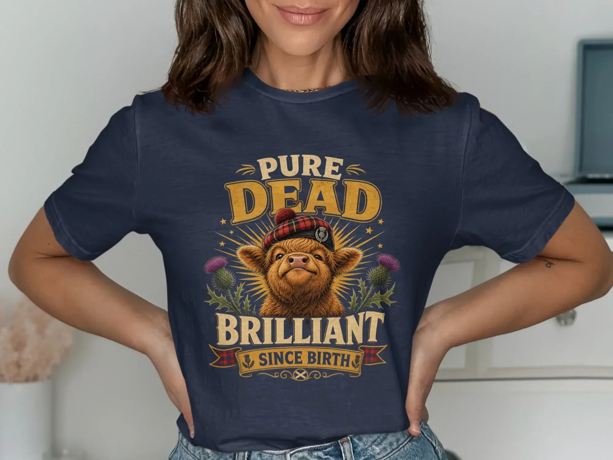 Navy t-shirt with a Scottish Highland cow graphic and "Pure Dead Brilliant" text.