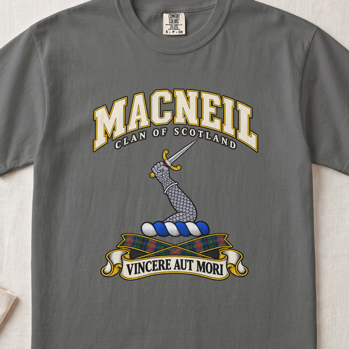 MacNeil Scottish clan T-shirt in Pepper, front view with an armoured arm holding a dagger and motto design.