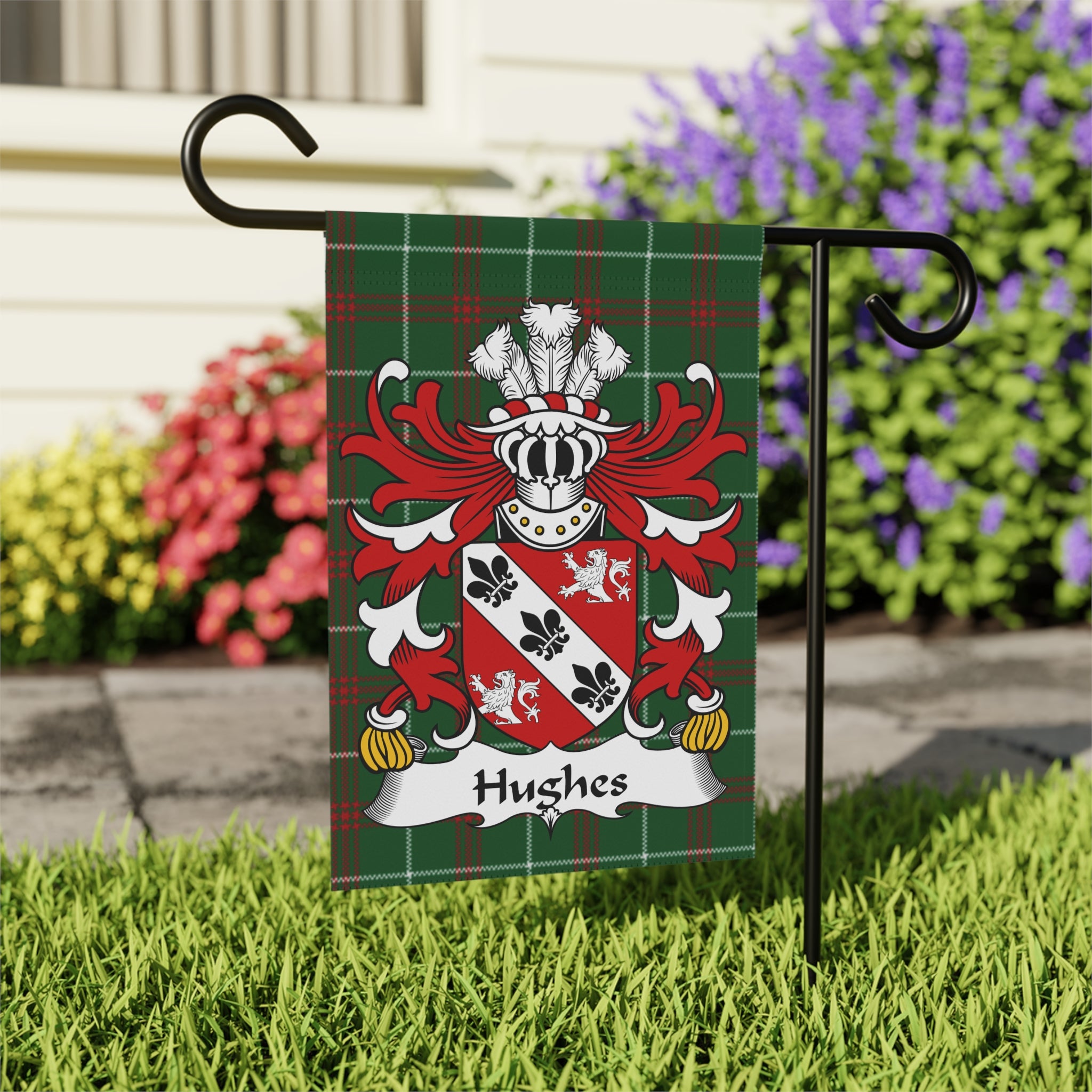 Hughes family crest on a tartan plaid garden flag outdoors.