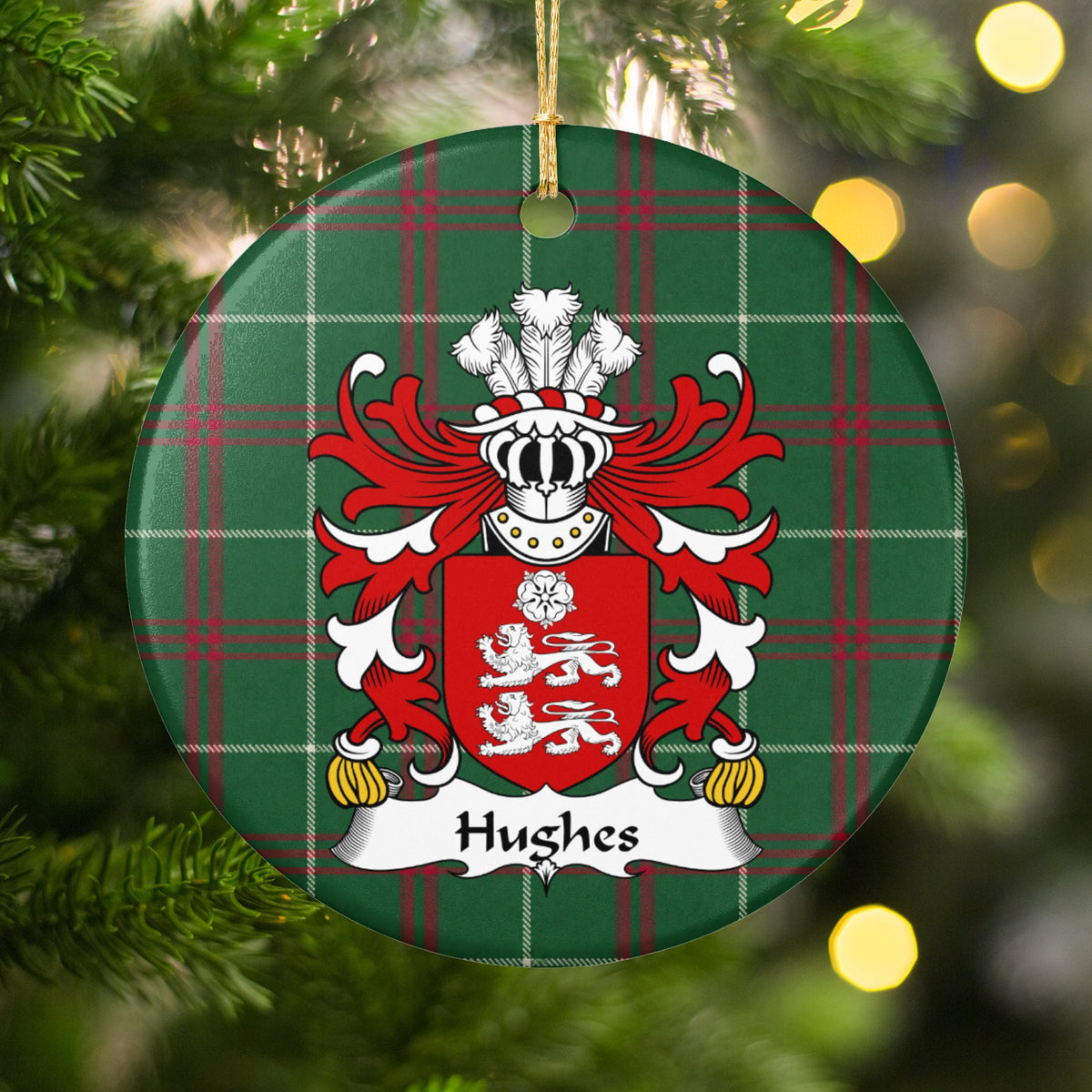 Hughes Style 3 ornament hanging among Christmas tree branches and warm lights; two white lions beneath a white rose on a red shield on Welsh national tartan.