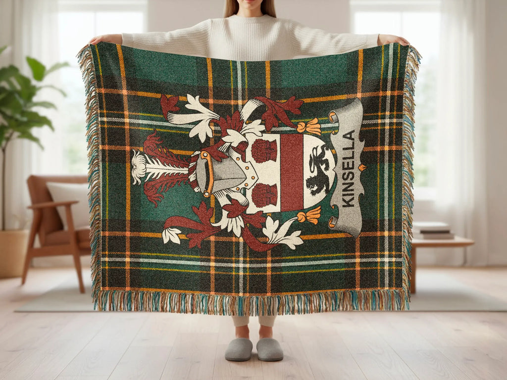 Plaid throw blanket with Kinsella crest and fringe held by a person.