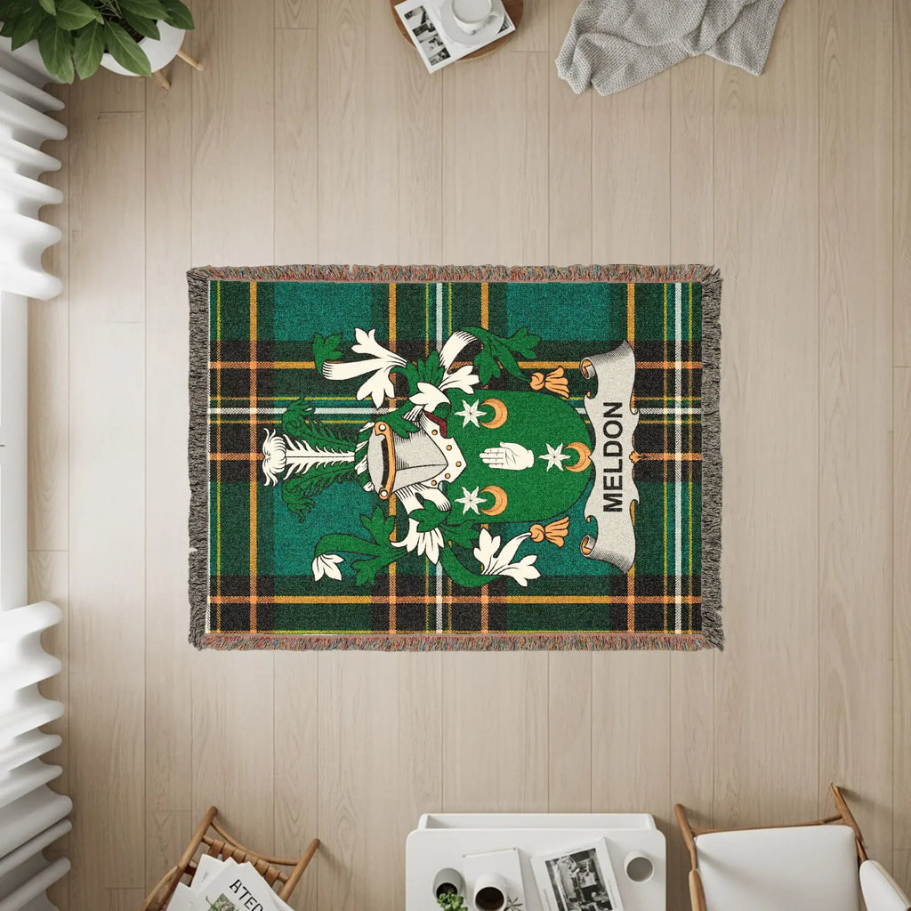 Green tartan blanket with a coat of arms featuring a shield and helmet, labeled "Meldon".