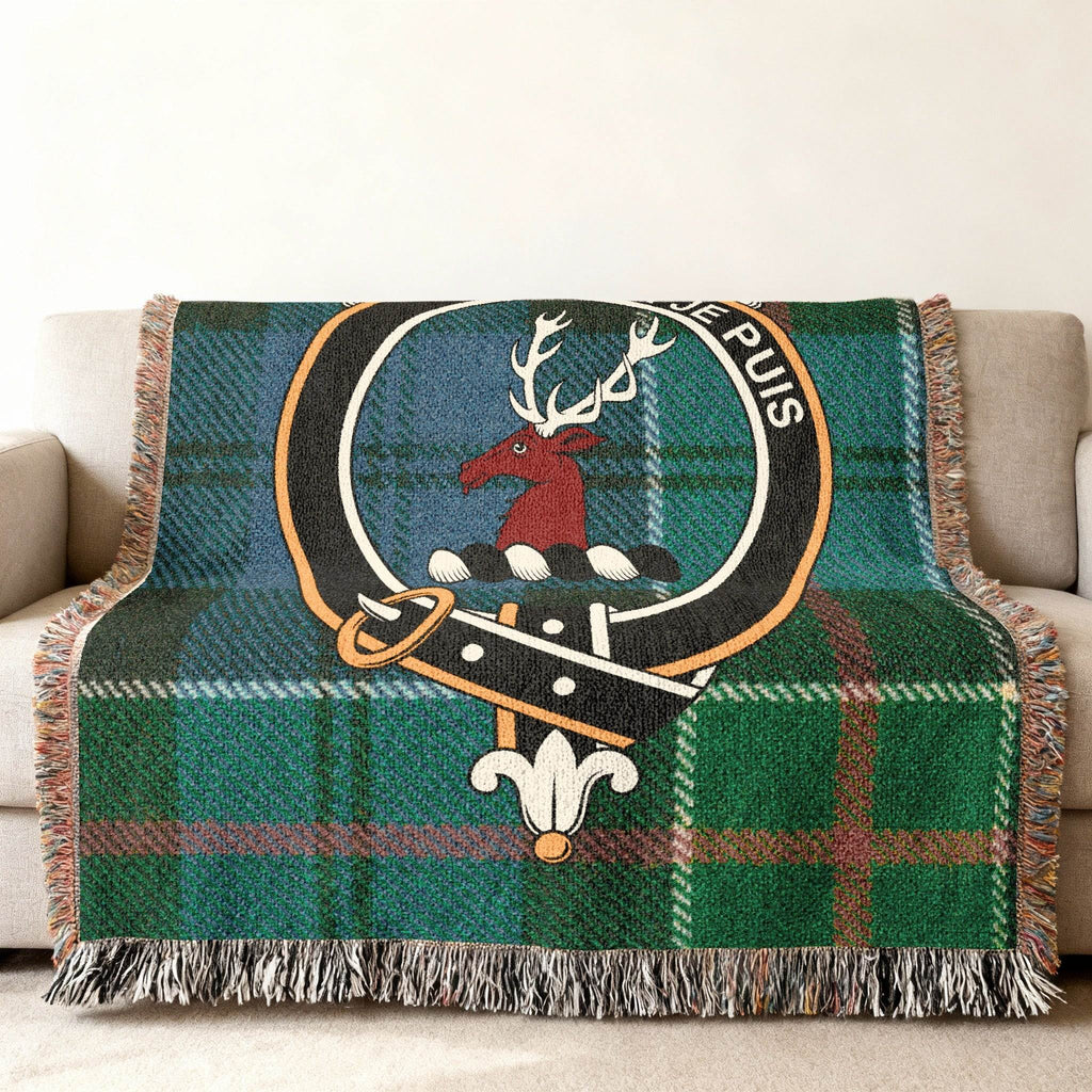 Colquhoun tartan woven blanket draped over armchair — fringe edges and stag crest detail