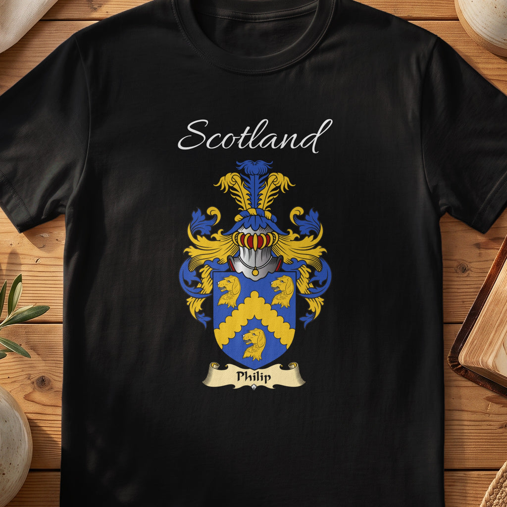 Black Philip Scottish family crest T-shirt laid flat, showing “Scotland” above a blue-and-gold shield with three gold wheat-sheaf-like emblems.
