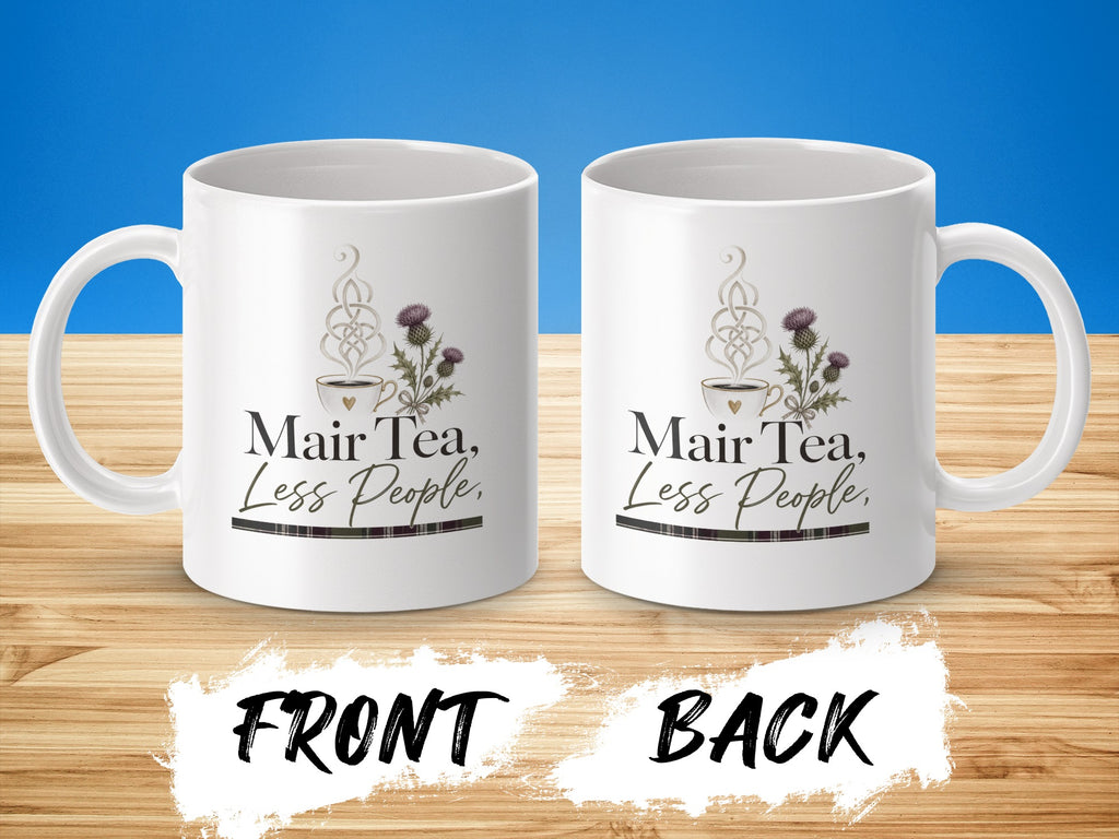 White mug with "Mair Tea, Less People" text and thistle design.