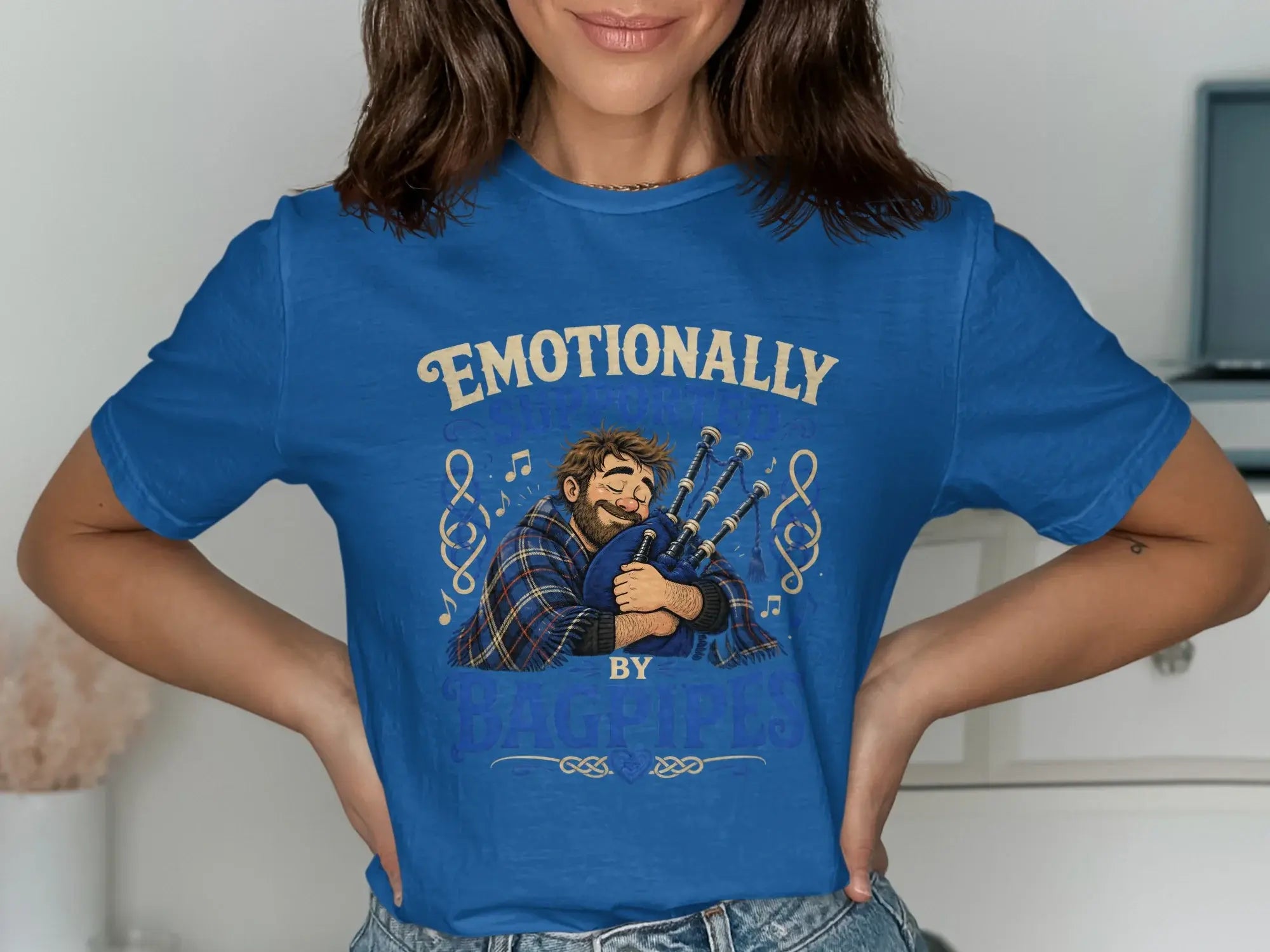 Blue t-shirt with a bearded man hugging bagpipes and the text "Emotionally by Bagpipes".