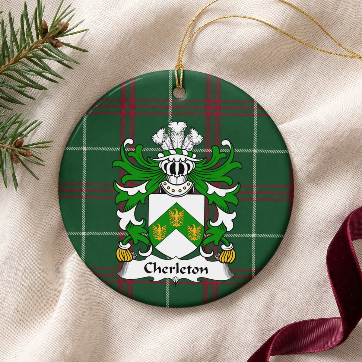 Cherleton ornament on cream fabric with gold string, evergreen and burgundy ribbon; three gold birds on a green chevron across a white shield on Welsh national tartan.