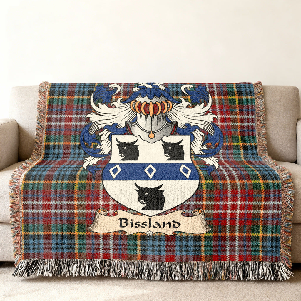 Bissland Scottish family shield woven blanket with Caledonia tartan background on a sofa