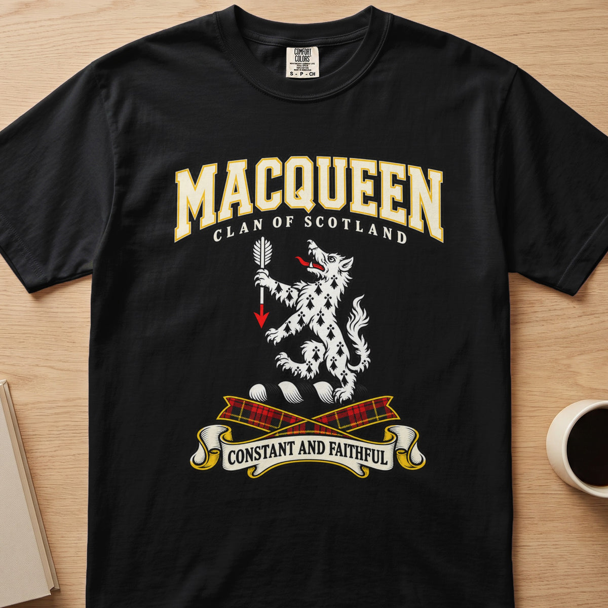 MacQueen white spotted animal crest graphic on a black Comfort Colors T-shirt, front view