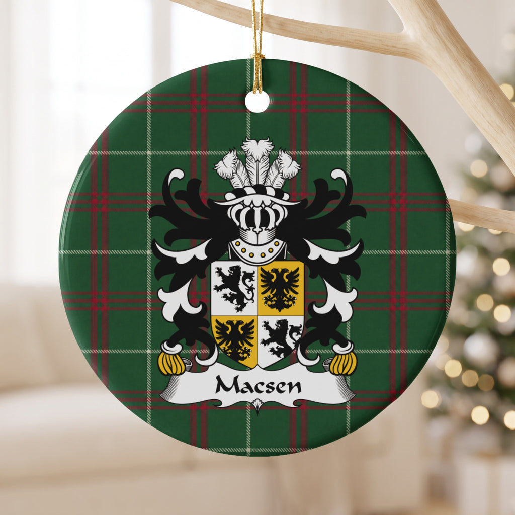 Macsen ornament hanging from a pale wooden branch, showing a quartered white-and-gold shield with black lions and eagles on Welsh National Tartan.