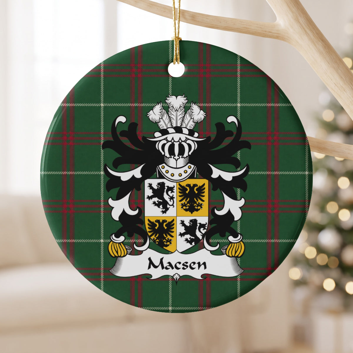 Macsen ornament hanging from a pale wooden branch, showing a quartered white-and-gold shield with black lions and eagles on Welsh National Tartan.