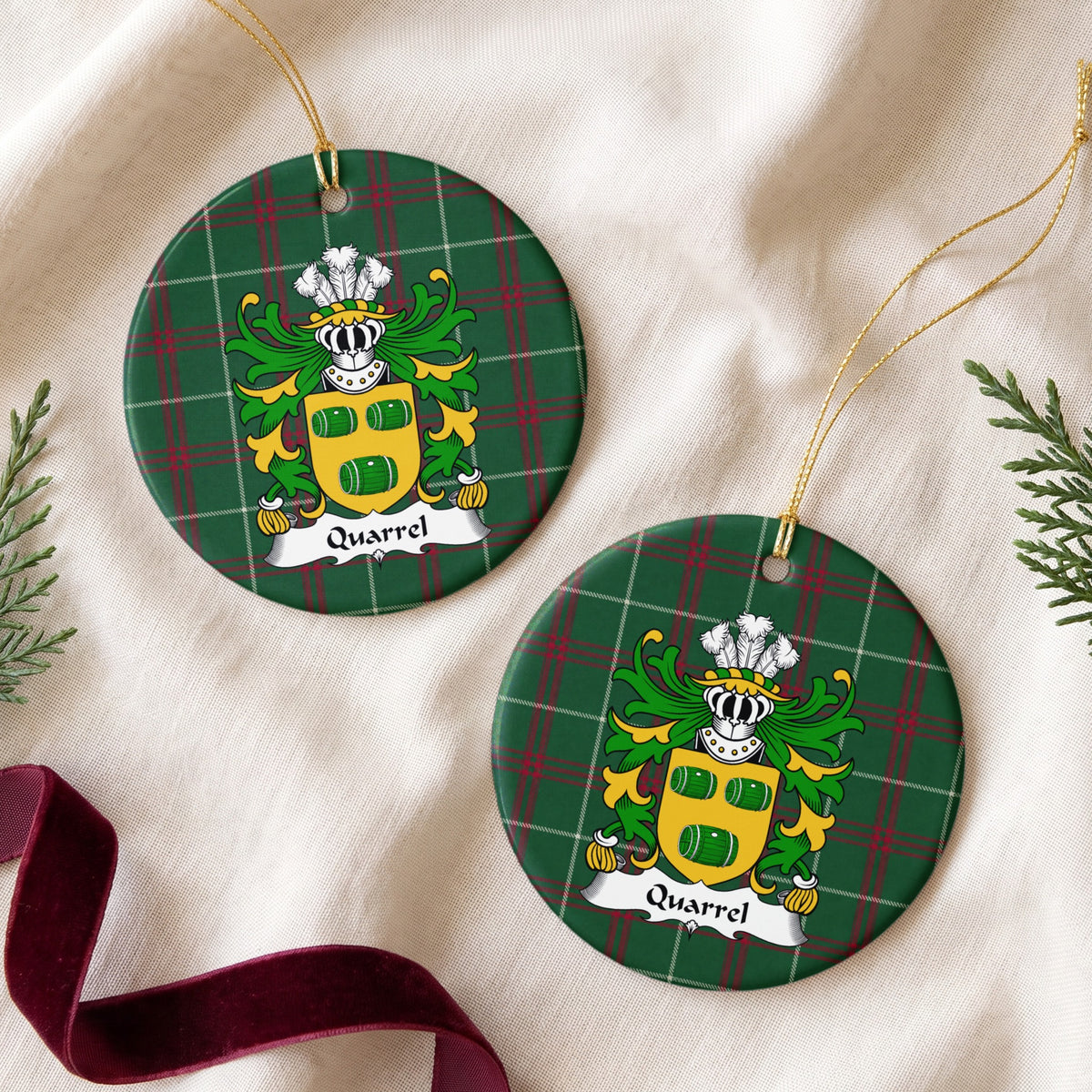 Quarrel round Welsh National Tartan ornament shown as a pair on cream fabric with evergreen sprigs and burgundy ribbon, featuring three green barrels on a gold shield.