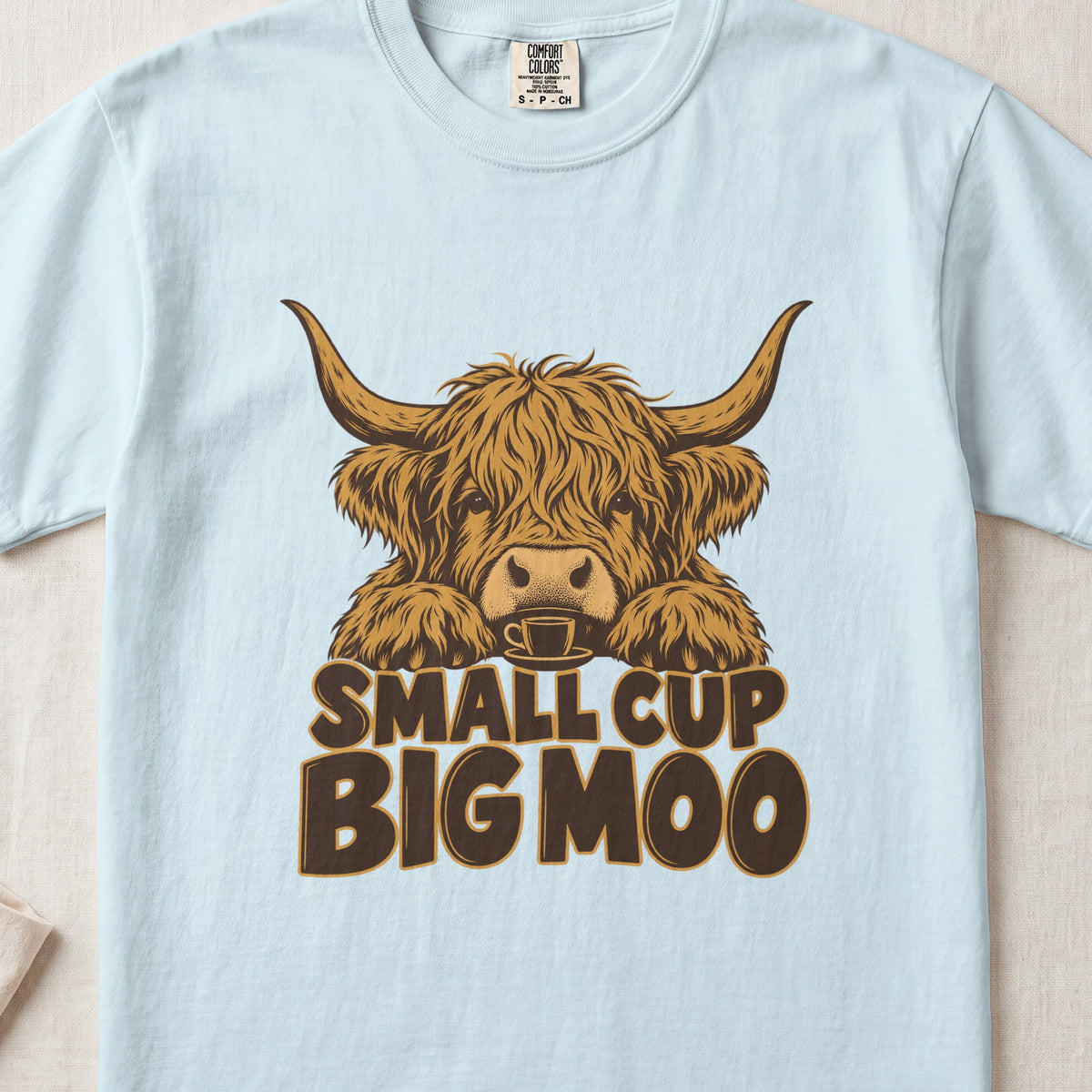 Small Cup, Big Moo Highland cow design on a Chambray Comfort Colors 1717 T-shirt, flat lay