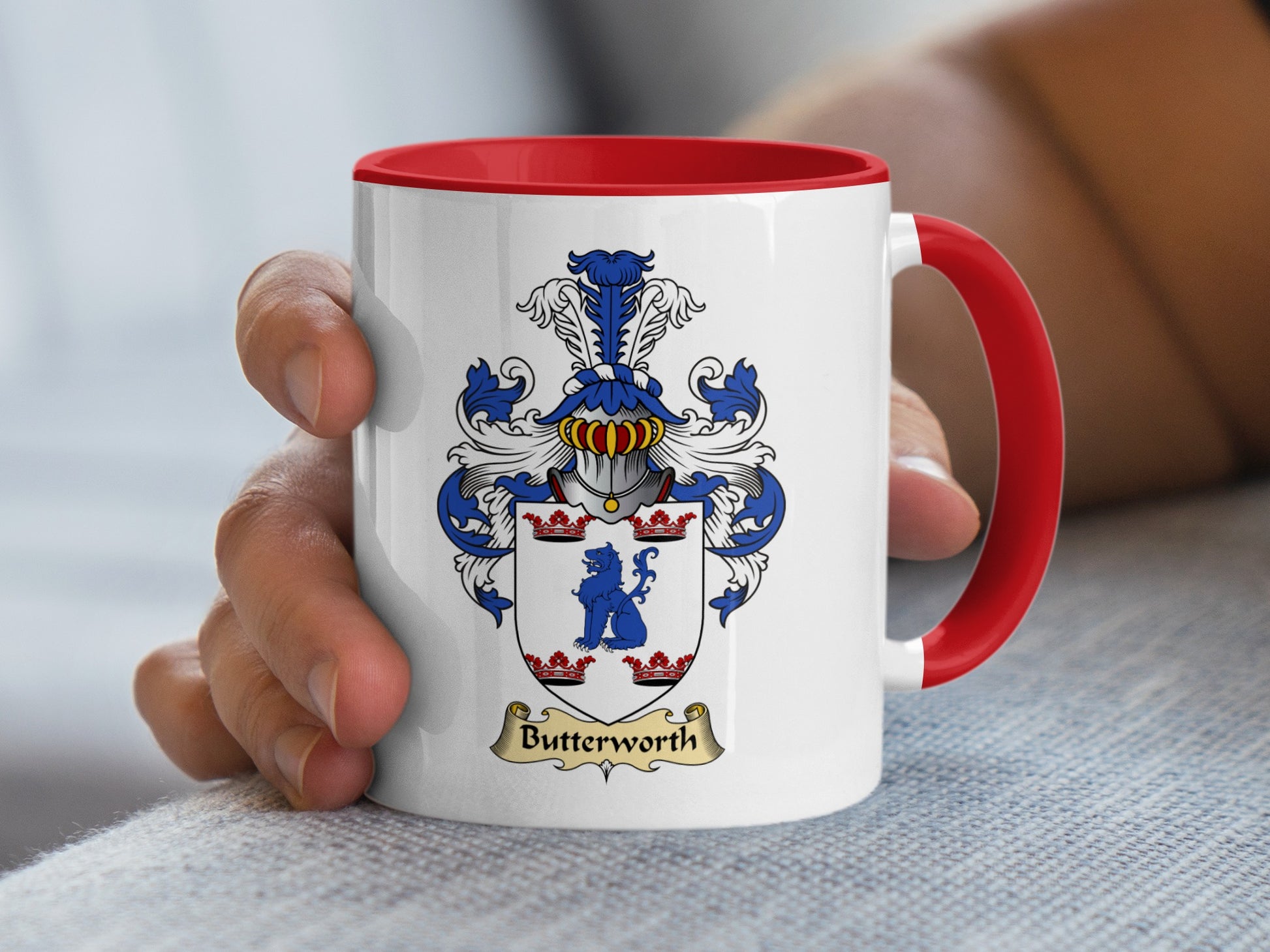 White mug with red handle, featuring a blue and gold Butterworth family crest.