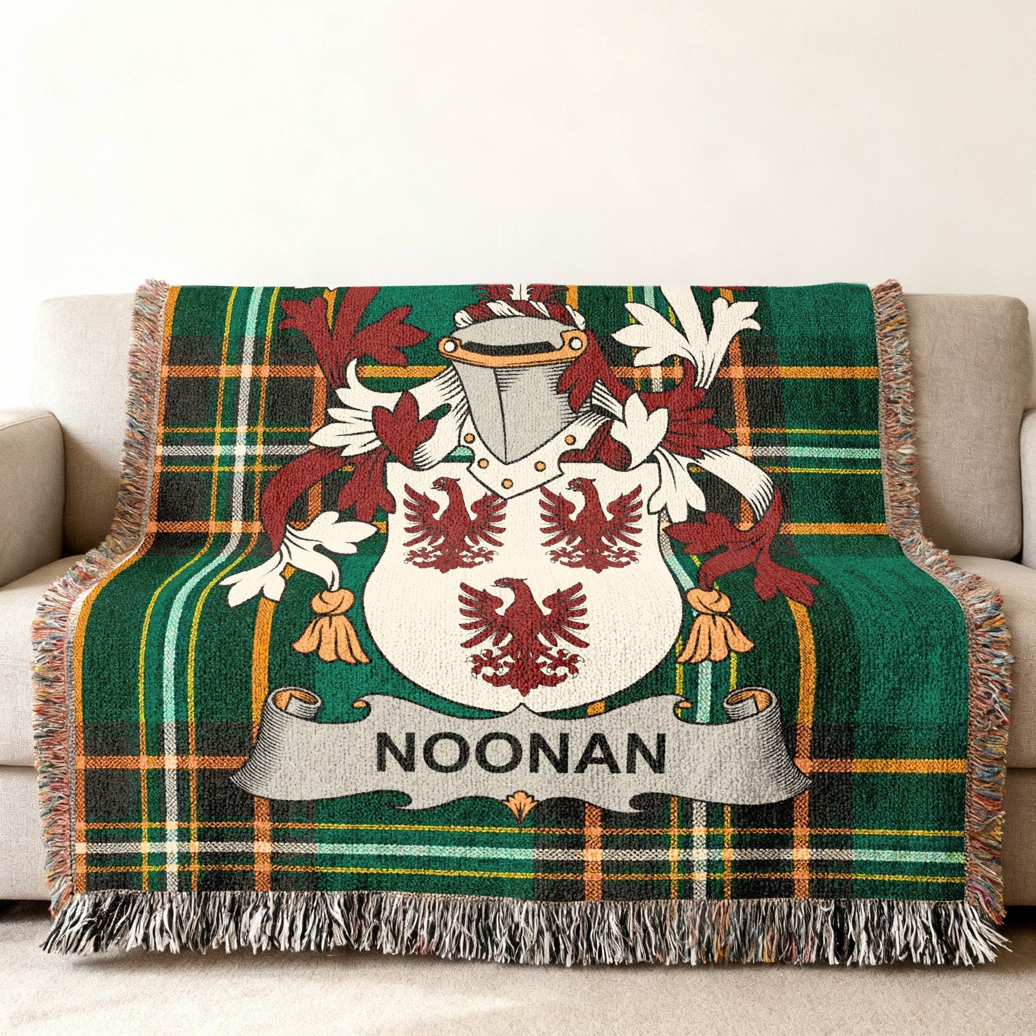 Green tartan blanket with Noonan family crest featuring two red birds on a shield.