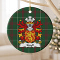 Knyll ceramic ornament hanging from a pale wooden branch, showing a red shield with a gold lion surrounded by small gold crosses on Welsh national tartan.