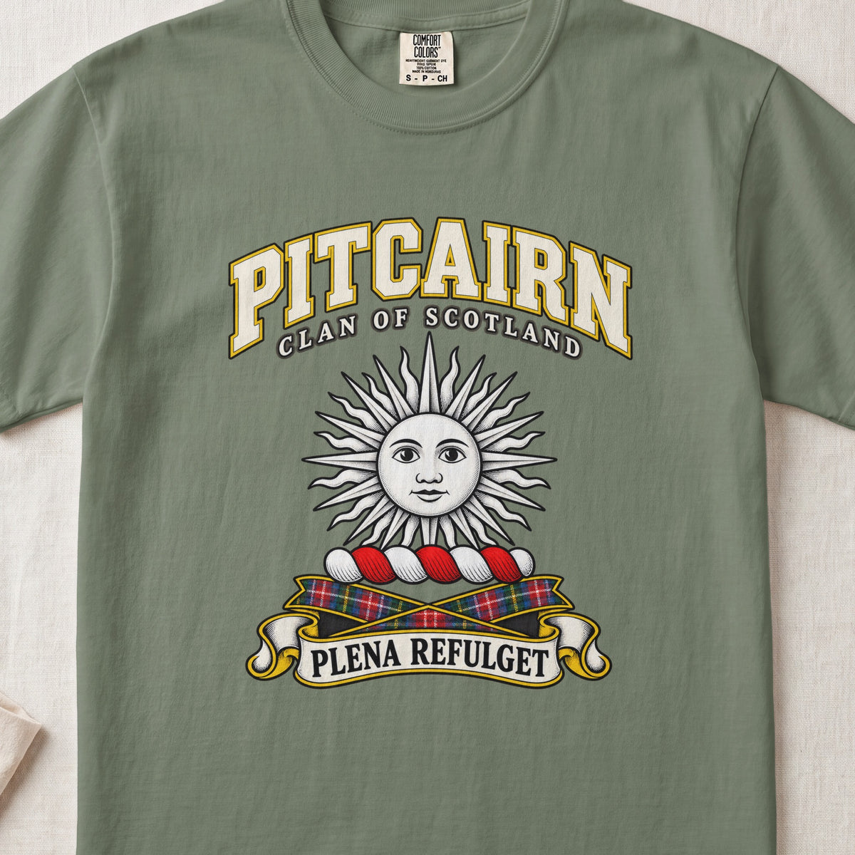 Pitcairn Scottish clan T-shirt in Moss, front view with a silver sun with a face and motto design.