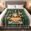 Wogan family crest on a green plaid woven blanket on a bed.