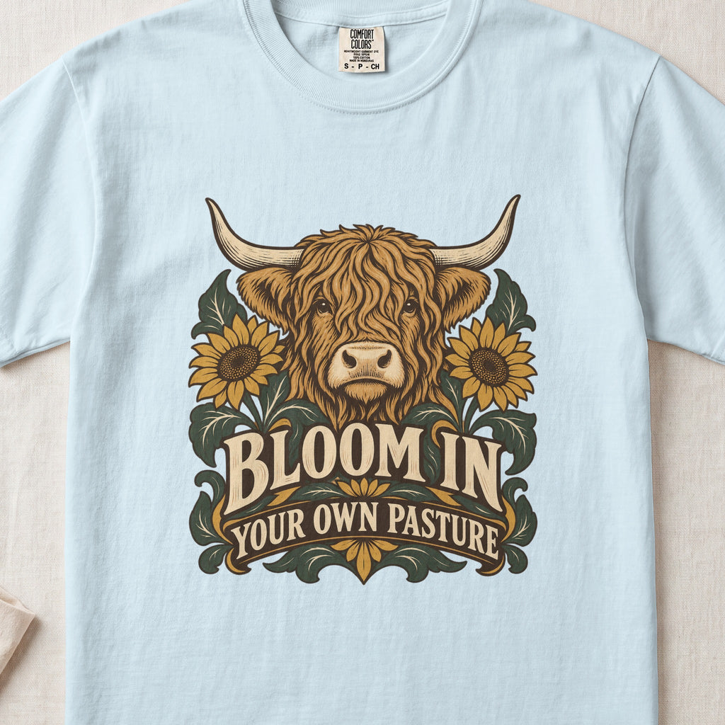 Bloom in Your Own Pasture Highland cow design on a Chambray Comfort Colors 1717 T-shirt, flat lay