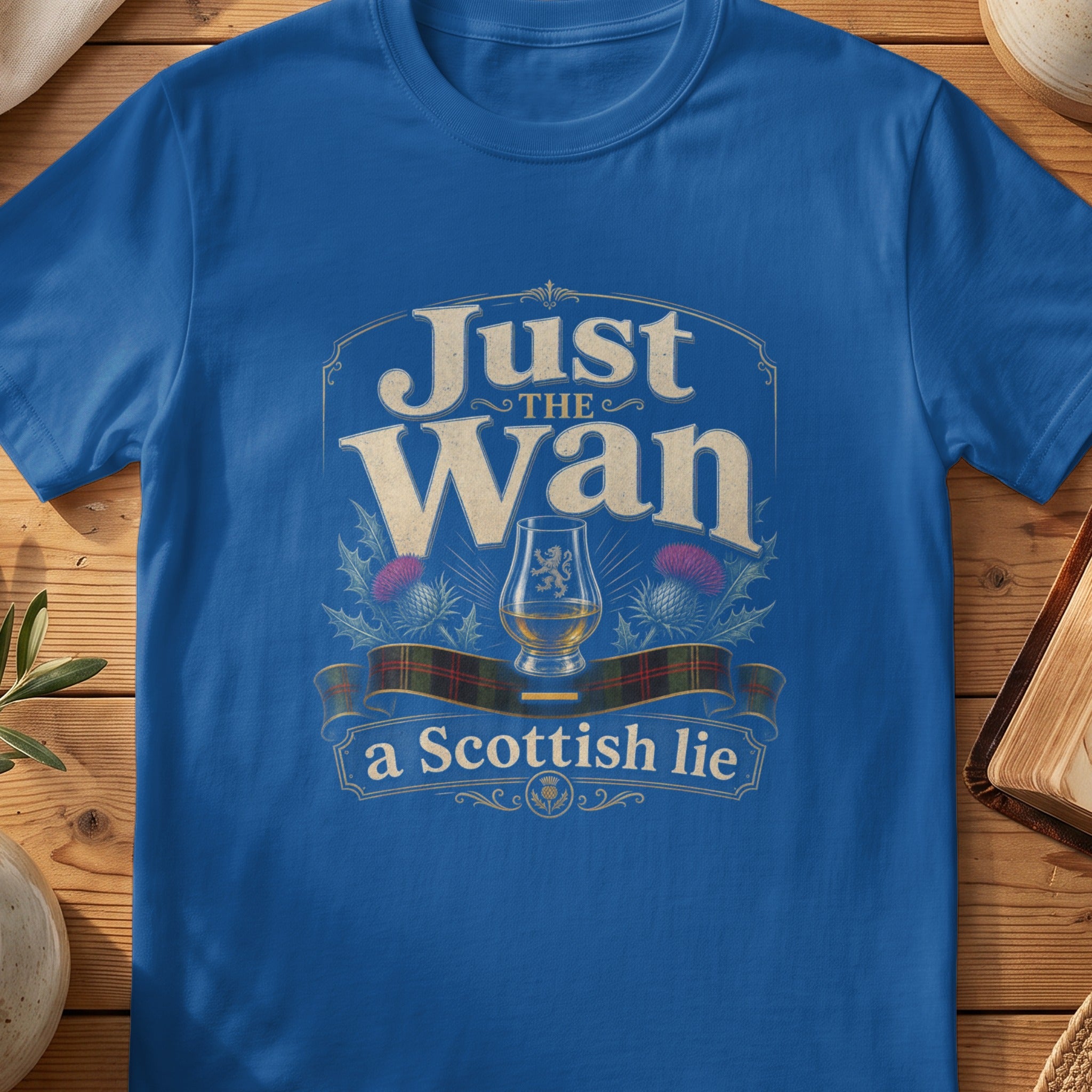 Blue t-shirt with text "Just the Wan, a Scottish lie" and Scotch glass.
