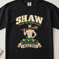Shaw Scottish clan T-shirt in Black, front view with a bearded figure carrying a wooden club over one shoulder and motto banner.
