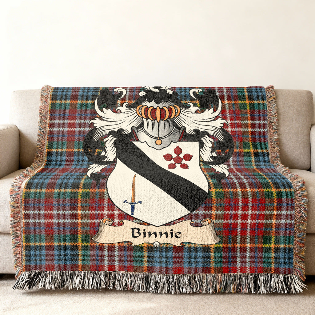Binnie Scottish family shield woven blanket with Caledonia tartan background on a sofa