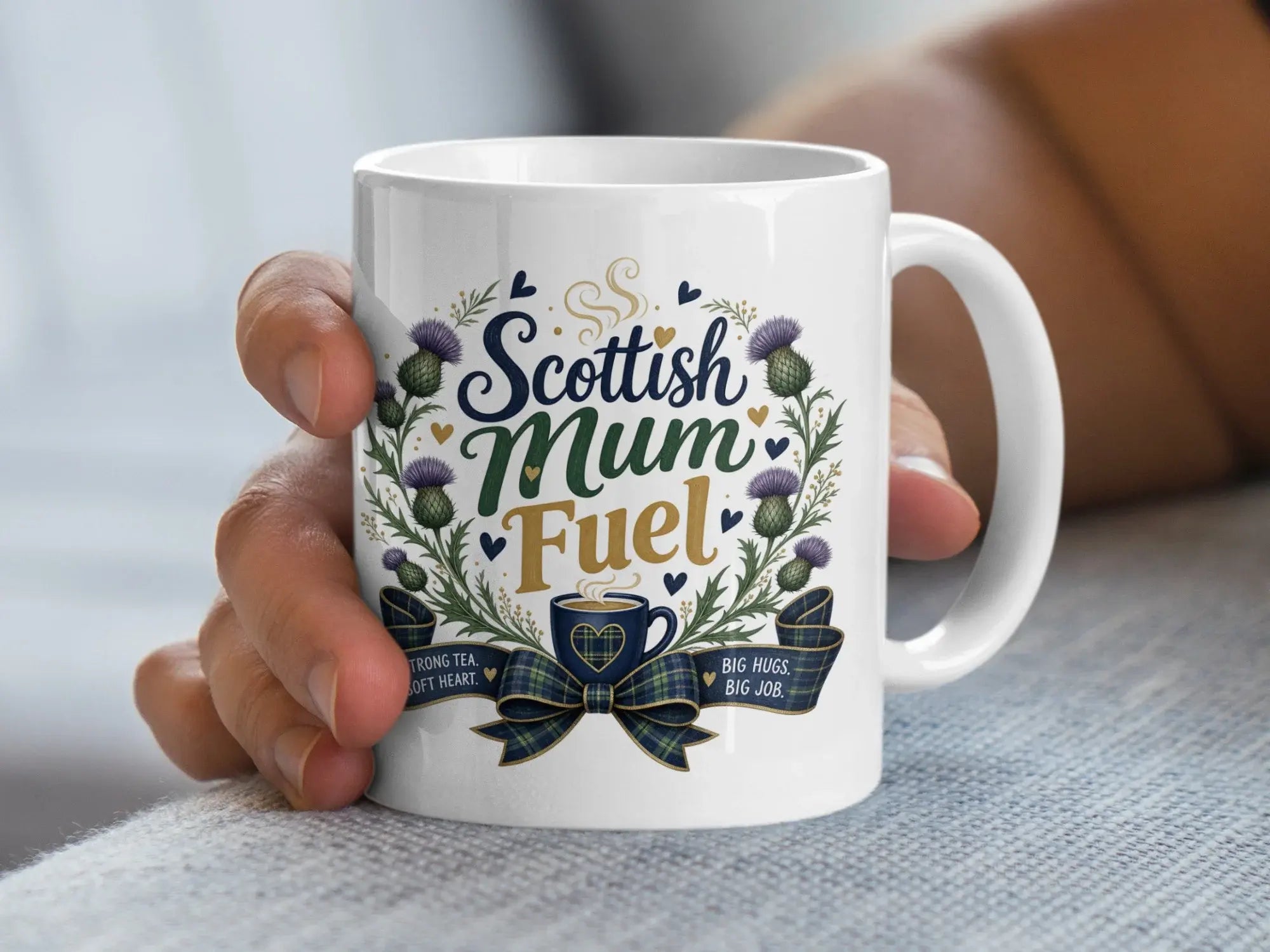 White mug with "Scottish Mum Fuel" text and thistles, held by a hand.