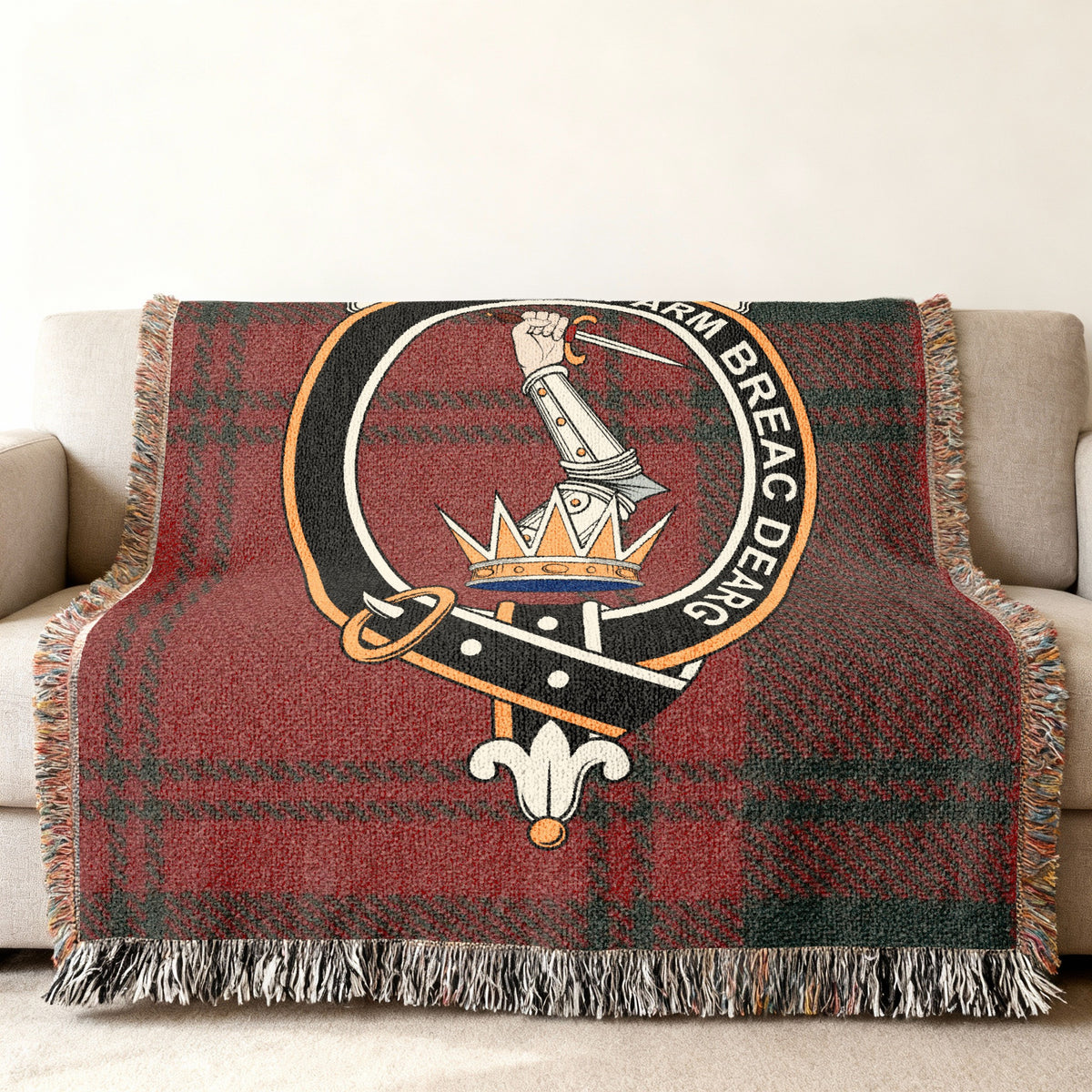 Close view of the MacQuarrie woven blanket draped over a sofa, showing the crest and fringed edges
