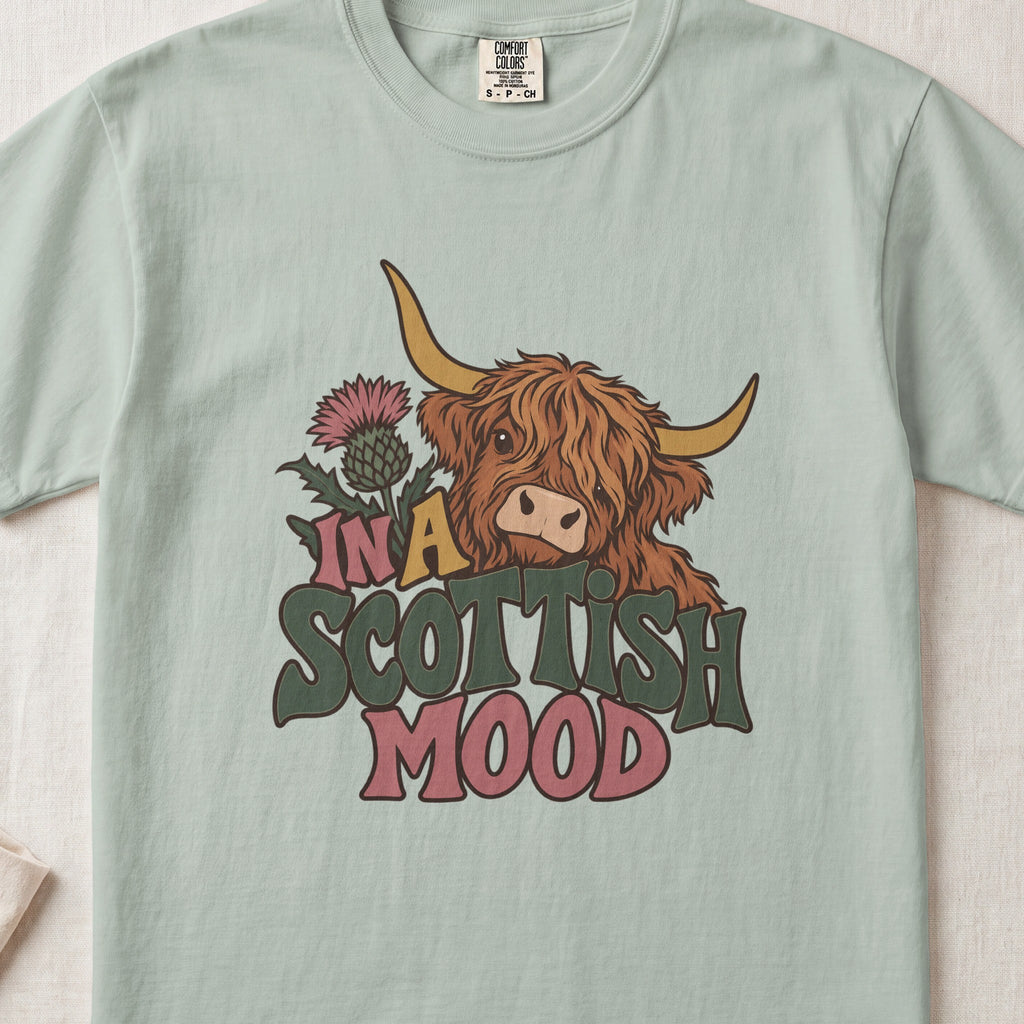 In a Scottish Mood Highland cow design on a Bay Comfort Colors 1717 T-shirt, flat lay