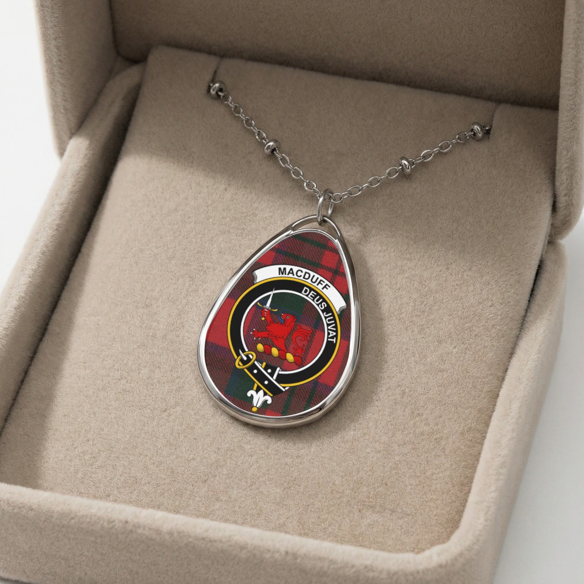 Oval silver necklace with Macduff clan crest on tartan background.