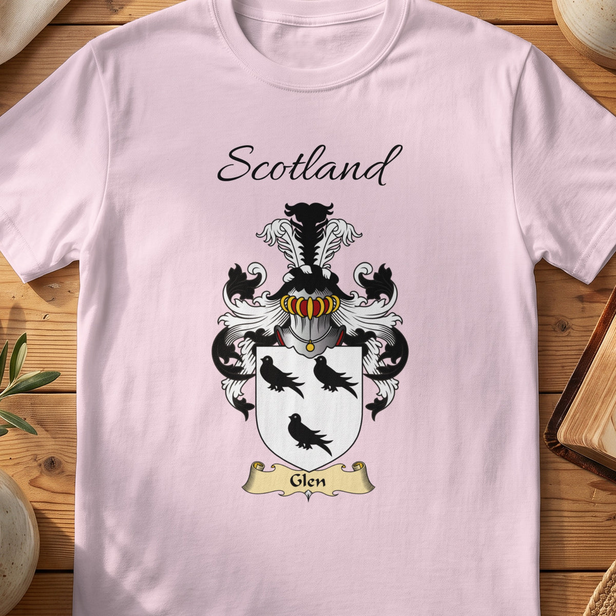 Light Pink Glen Scottish family shield T-shirt featuring three black birds on a white shield