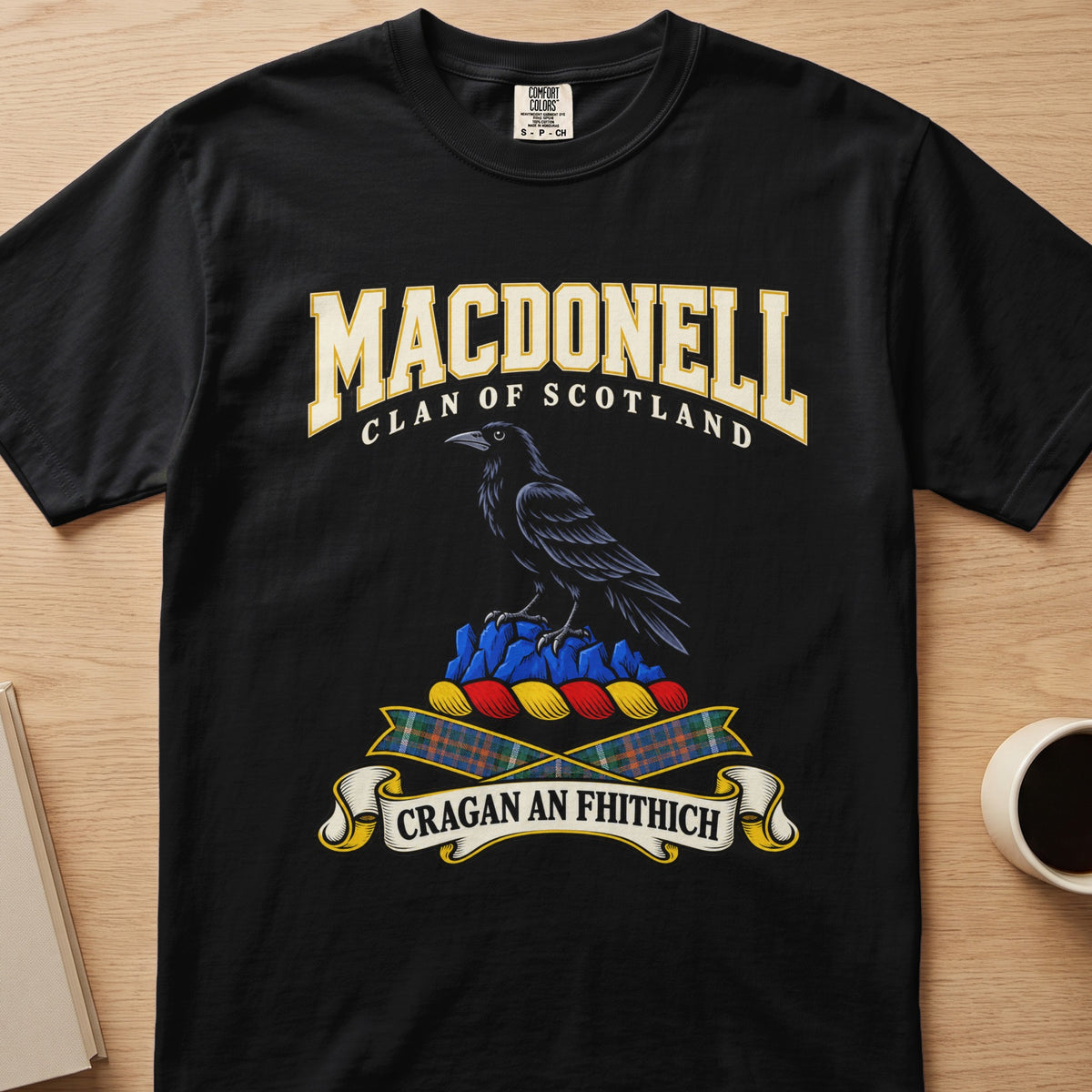MacDonell dark bird perched on blue rocks graphic on a black Comfort Colors T-shirt, front view