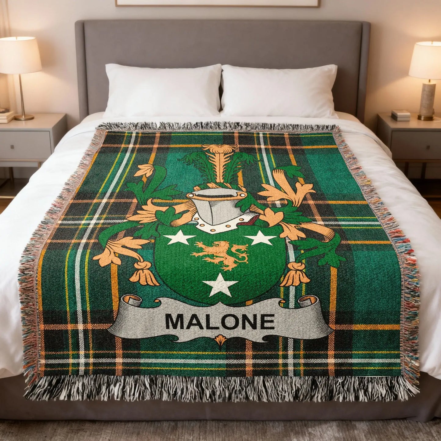Green tartan blanket with Malone family crest on a bed.