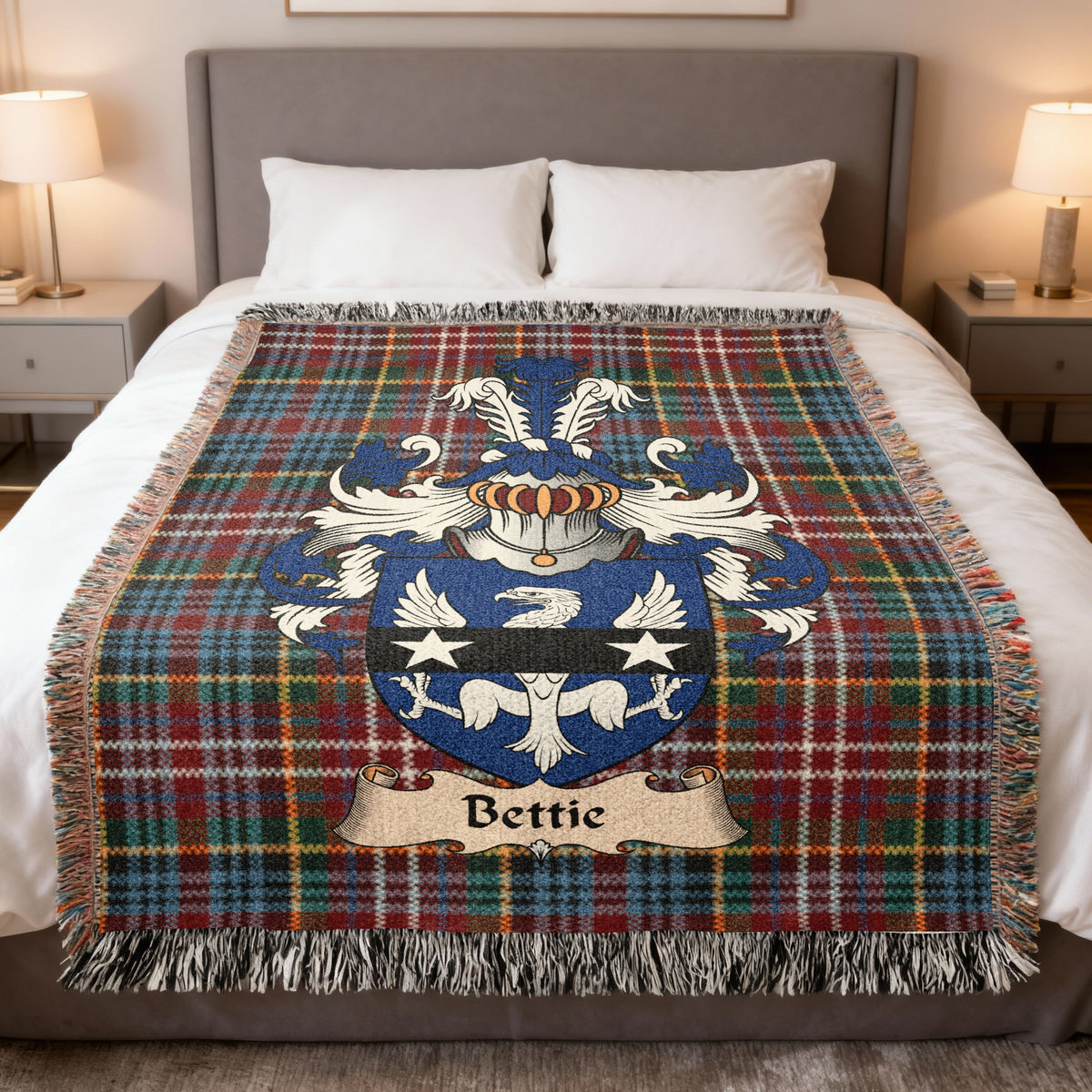 Bettie Scottish family crest woven blanket on a Caledonia tartan background, displayed on a bed