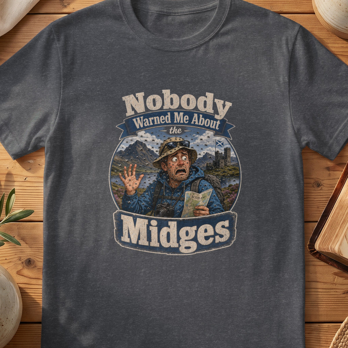 Dark grey Gildan 64000 unisex T-shirt flatlay with Nobody Warned Me About the Midges Scottish graphic design