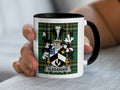 White mug with black rim featuring a plaid pattern and the Alexander family crest.