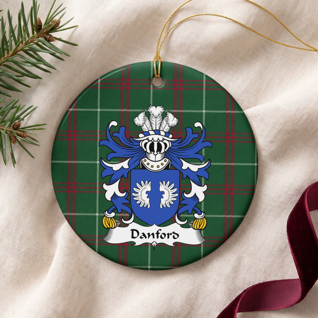 Danford ornament on cream fabric with gold string, evergreen and burgundy ribbon; two white wings on a blue shield.