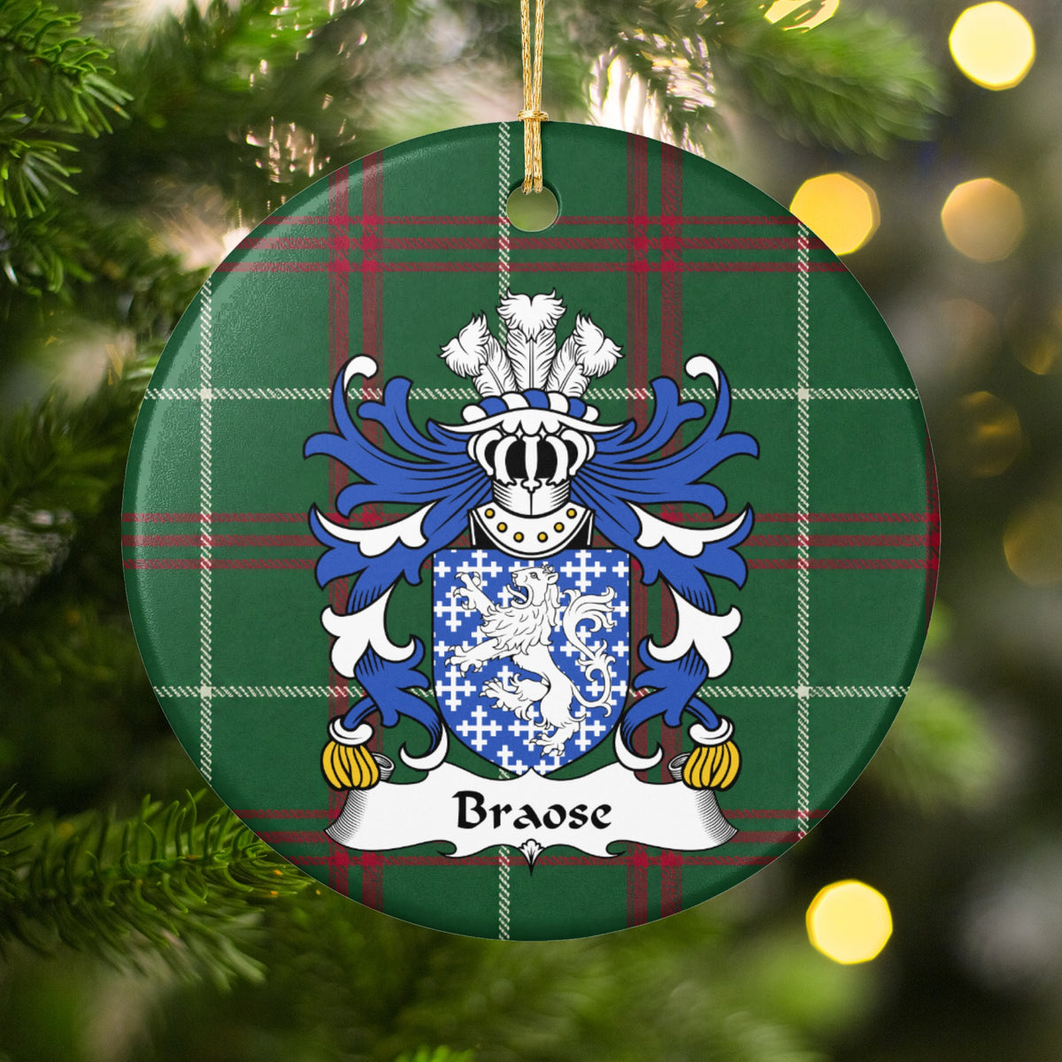 Braose ornament hanging in a Christmas tree with warm lights; a white lion and small white crosses on blue on Welsh national tartan.