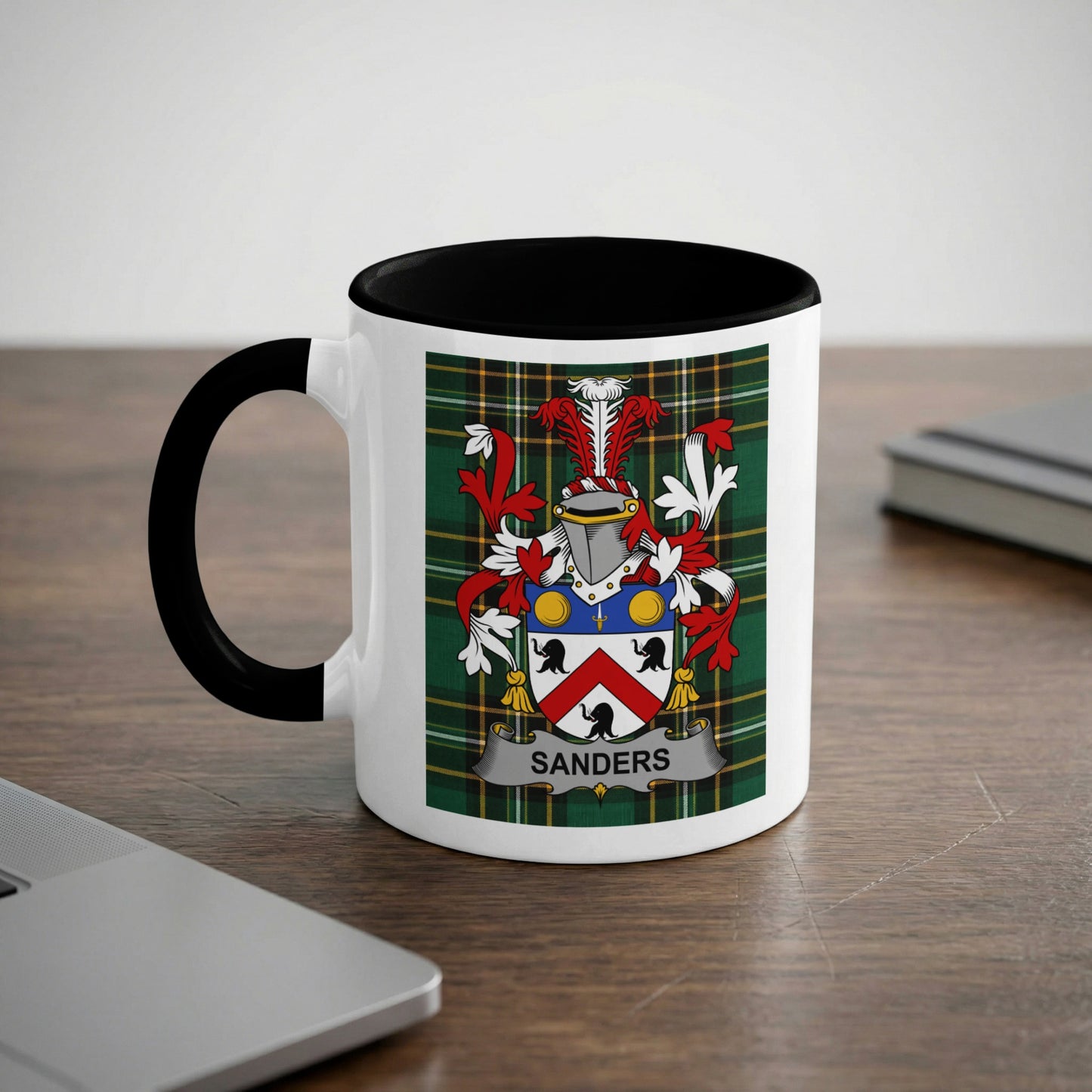 White mug with black rim displaying Sanders family crest on a plaid background.