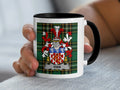 Mug with Vian family crest on tartan background held by a hand.