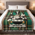 Plaid throw blanket with Newsom family crest and fringe on a bed.
