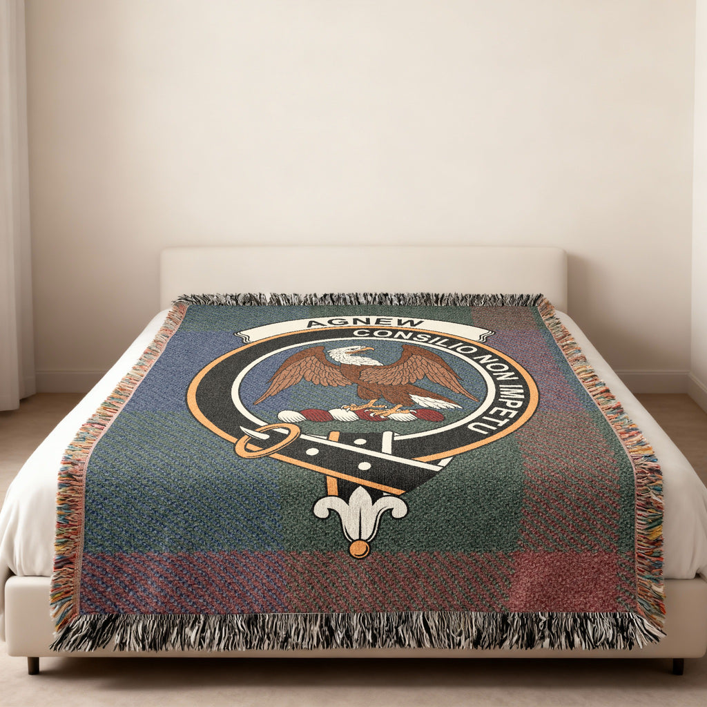Agnew Scottish woven blanket spread across a bed, showing the full crest design and tartan background