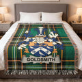 Goldsmith family crest on a green plaid throw blanket on a bed.