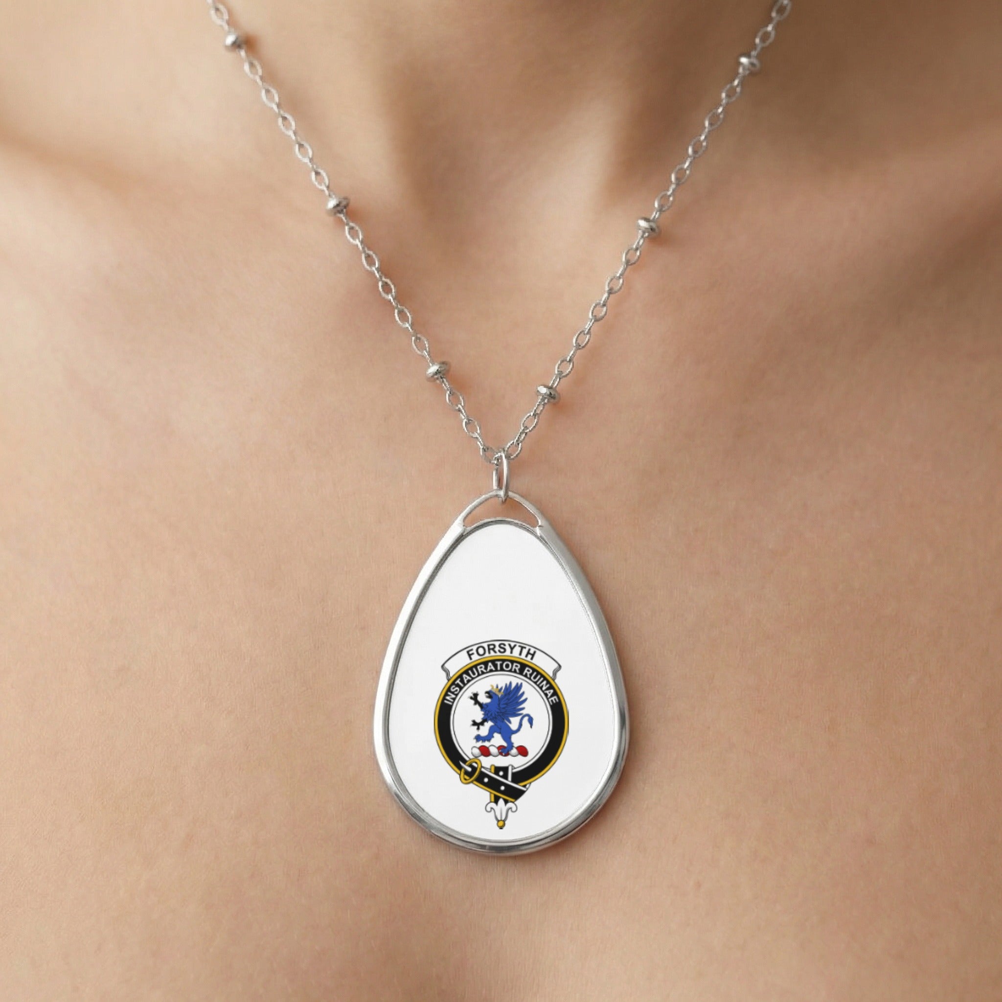 Oval pendant necklace with Forsyth crest featuring a blue winged lion and motto.