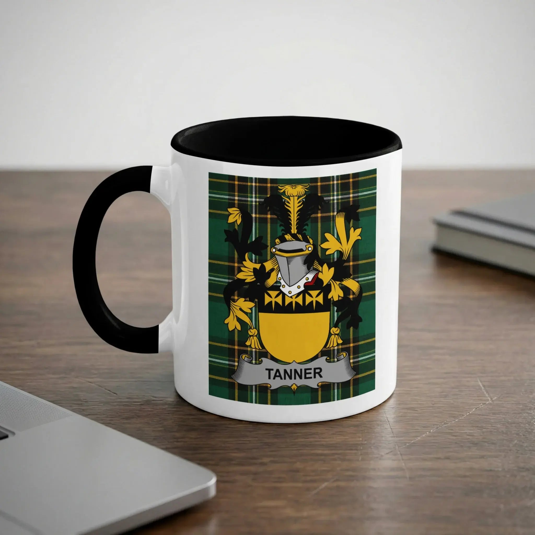 White mug with black rim featuring the Tanner family crest on a plaid background.