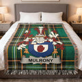 Tartan blanket with Mulroney clan crest on a bed.